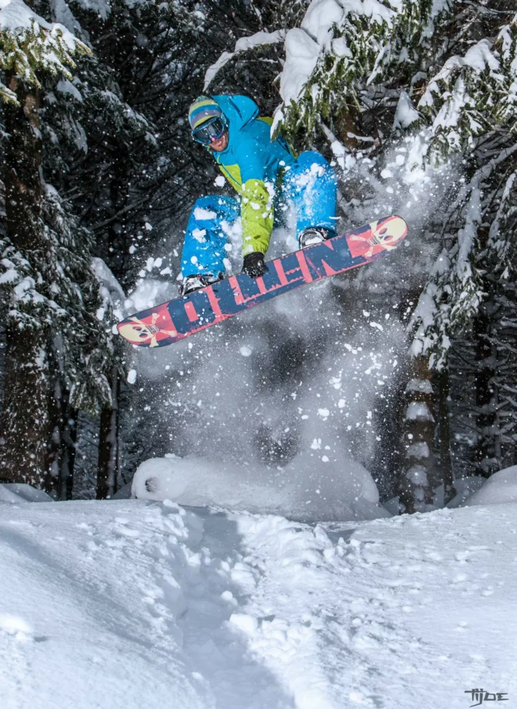 Snowboard freestyle dans les Vosges – Tijoe photographe Mulhouse Snowboarder en plein saut dans une forêt enneigée des Vosges