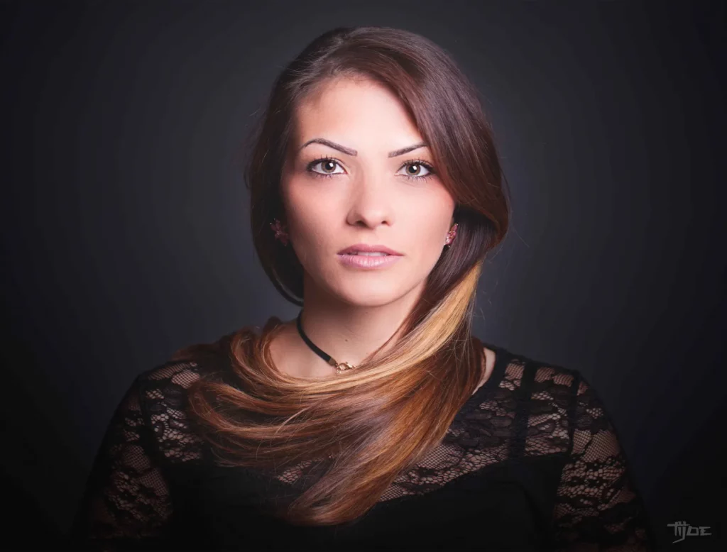 Portrait professionnel en studio – lumière douce, fond noir – Tijoe, photographe à Mulhouse Portrait de femme en studio avec éclairage doux et fond noir