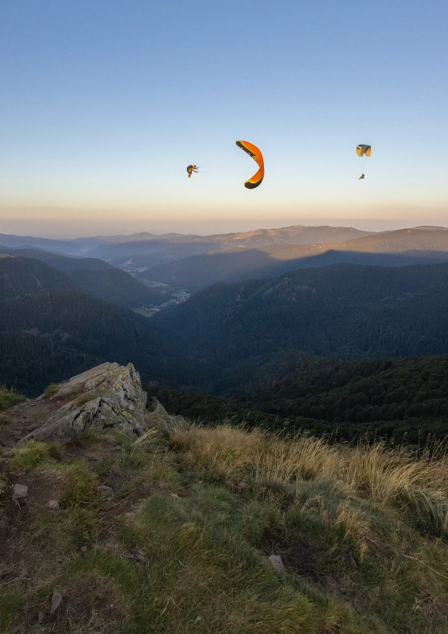 Parapente en vol au-dessus des montagnes – Tijoe photographe en Alsace Parapentes en vol au-dessus des montagnes des Vosges au coucher du soleil, photo de Tijoe photographe en Alsace.