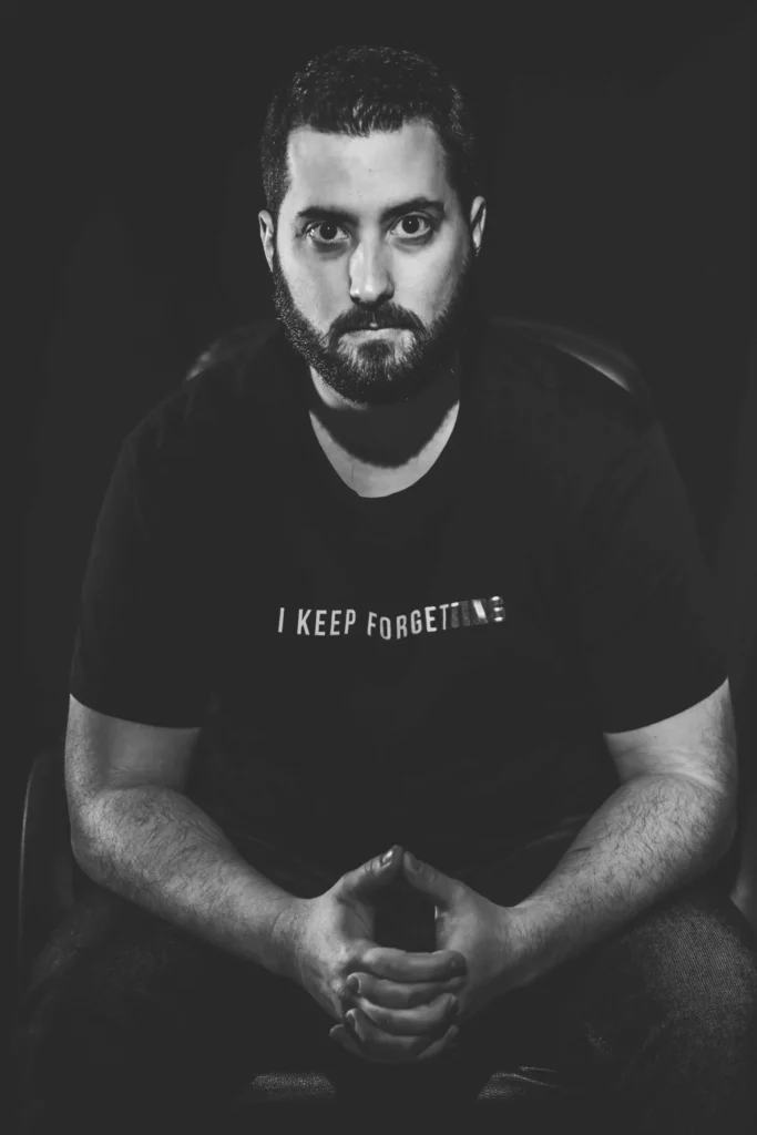 Portrait en noir et blanc d’un homme assis, regard intense, ambiance studio sombre